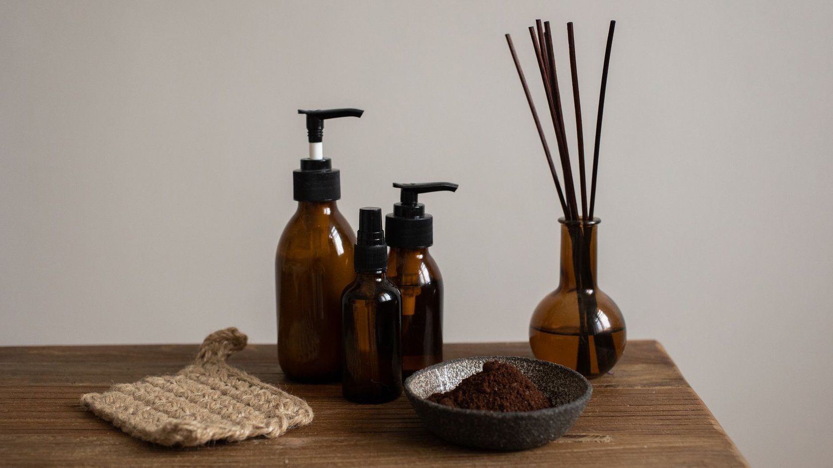 Difusor de varetas e frascos âmbar sobre mesa de madeira, formatos de aroma para lavabo