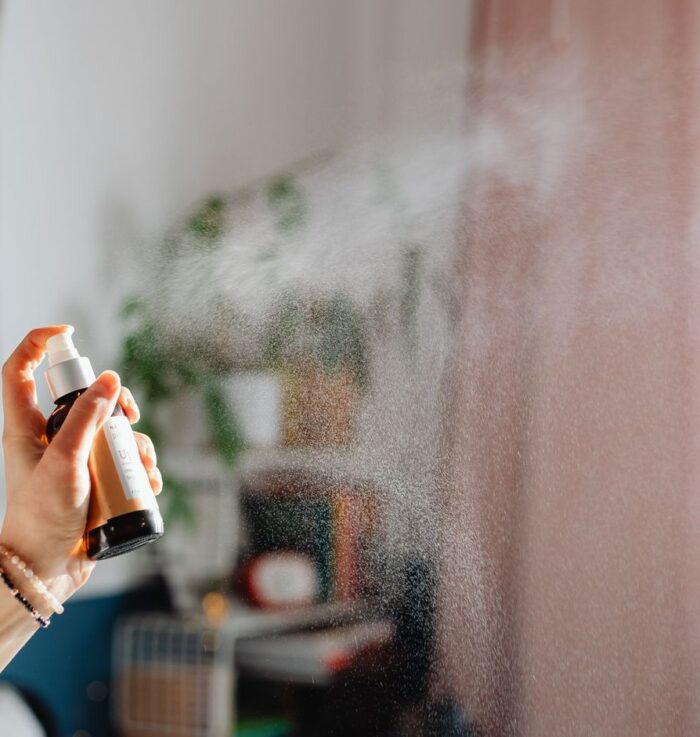 Home spray sendo aplicado em ambiente de casa, representando aromas cítricos, florais e amadeirados