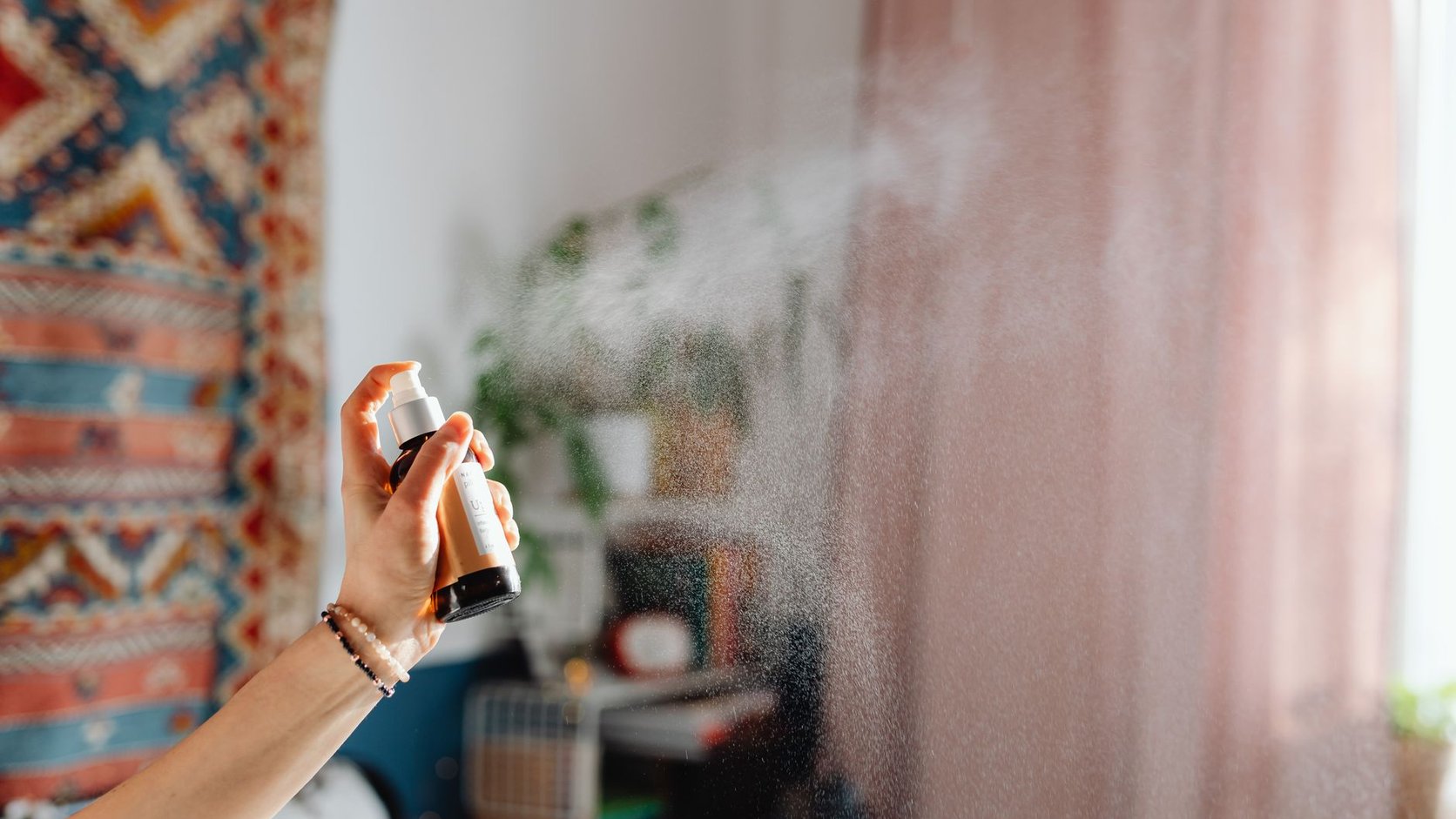 Home spray sendo aplicado em ambiente de casa, representando aromas cítricos, florais e amadeirados