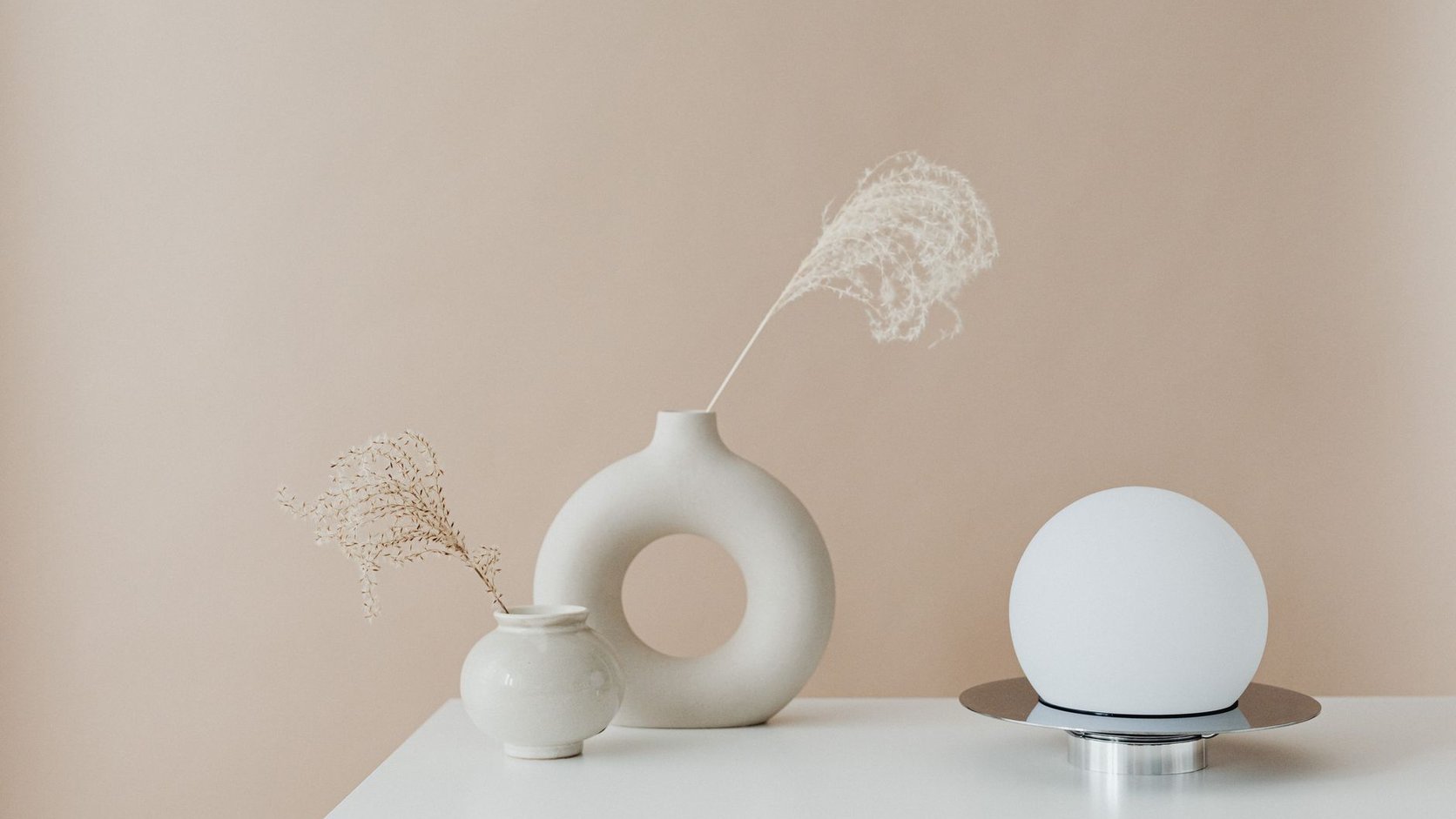Aparador com luminária, vasos decorativos e composição neutra