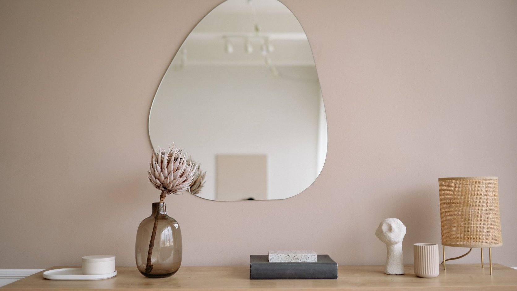 Aparador de sala com espelho, vaso e luminária em composição minimalista