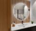 Lavabo com espelho arredondado, madeira ripada e iluminação suave em composição acolhedora