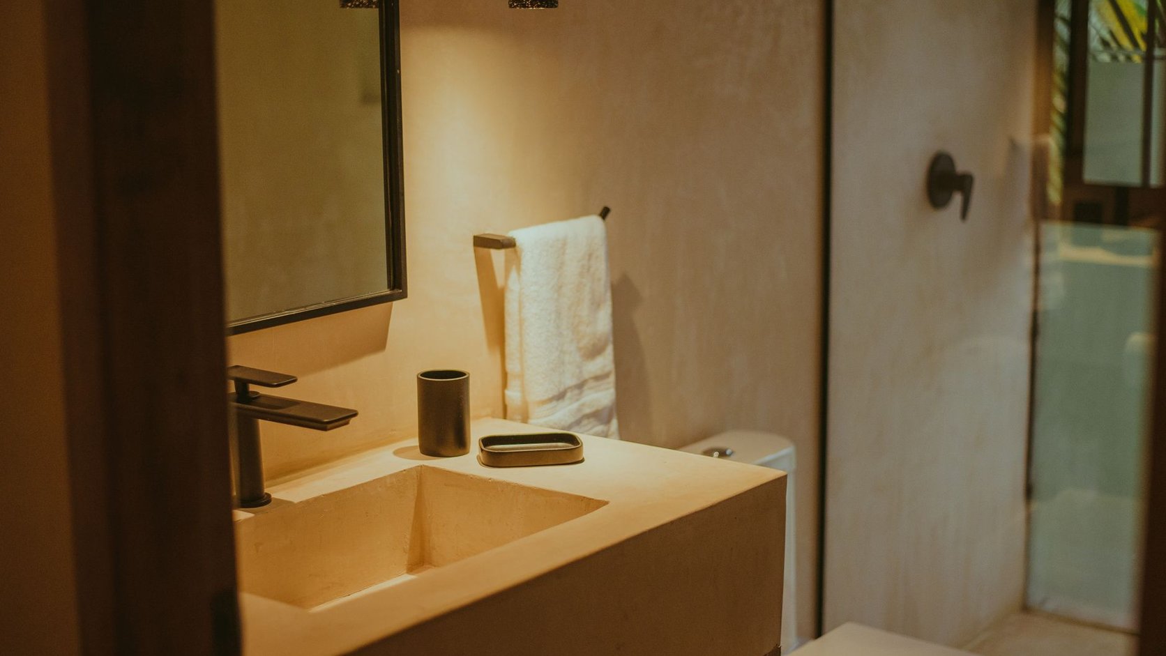 Lavabo com luz suave, toalha de apoio e bancada organizada com poucos elementos